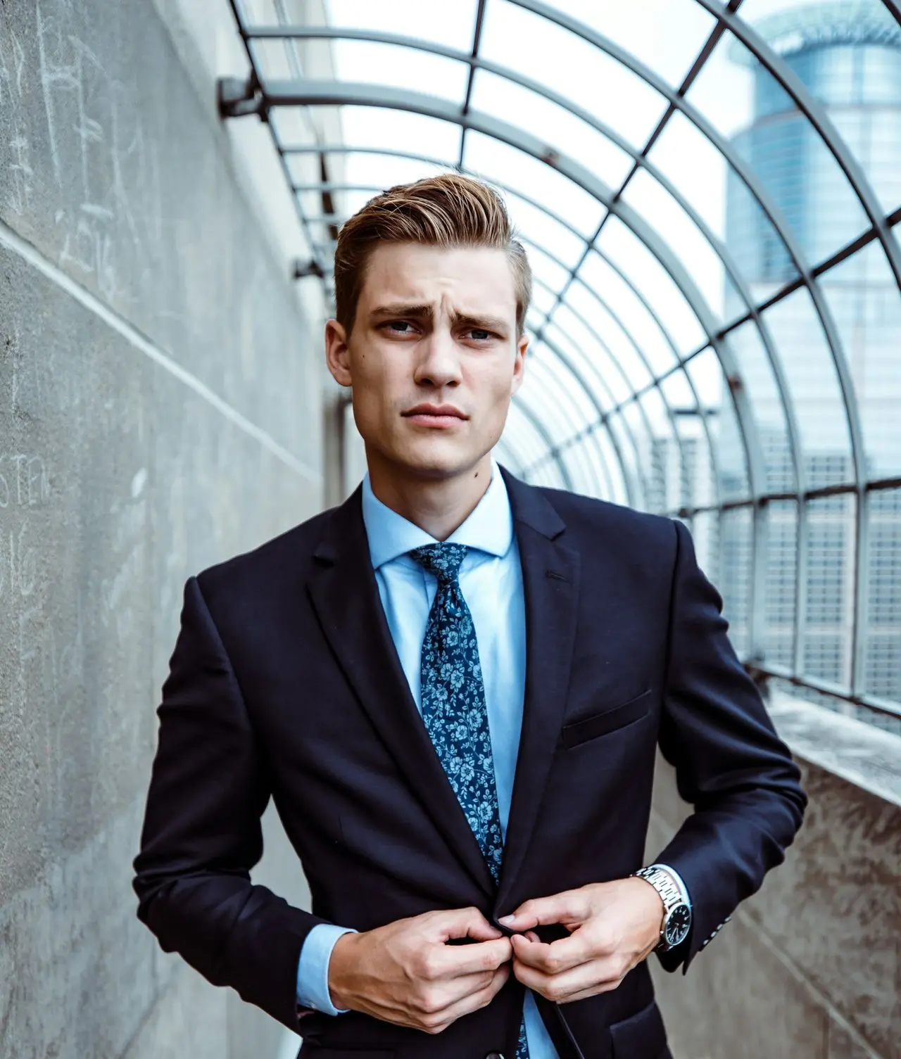 man wearing black and teal dress suit standing near gray wall